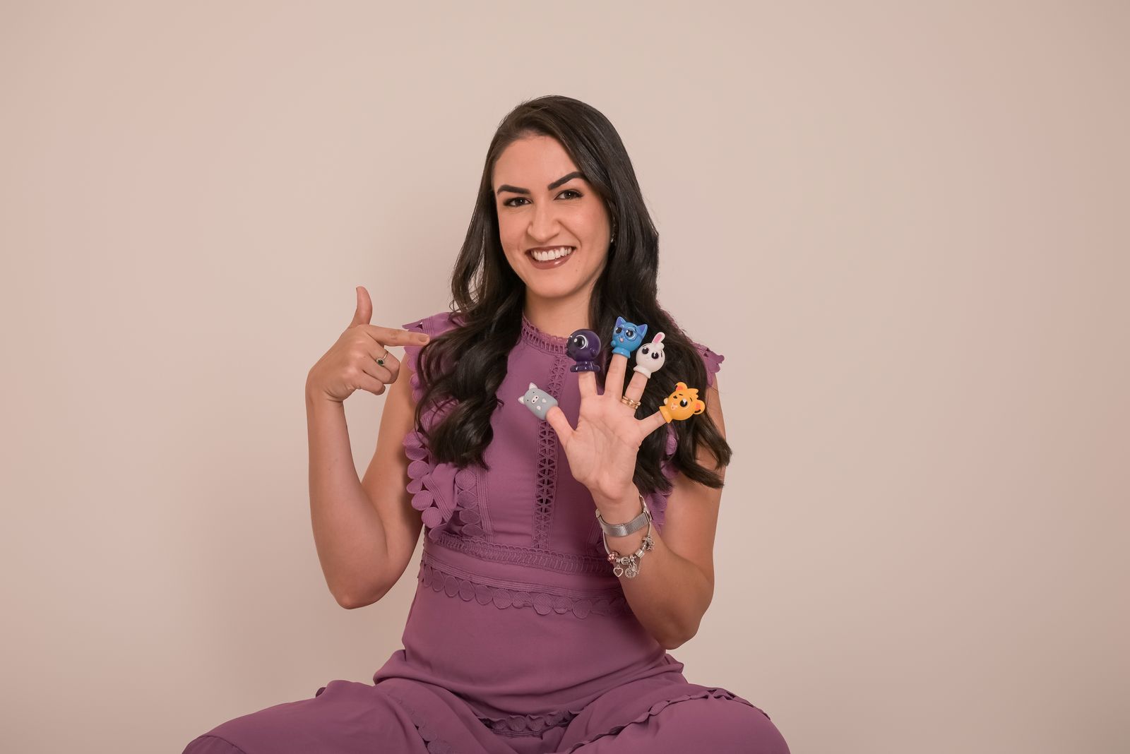 Dra. Carol Nogueira sorrindo, com fantoches de dedo coloridos